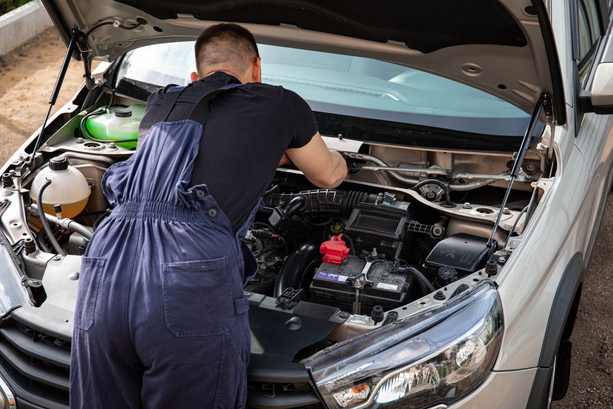 Mechanic working on a car engine in an outdoor setting